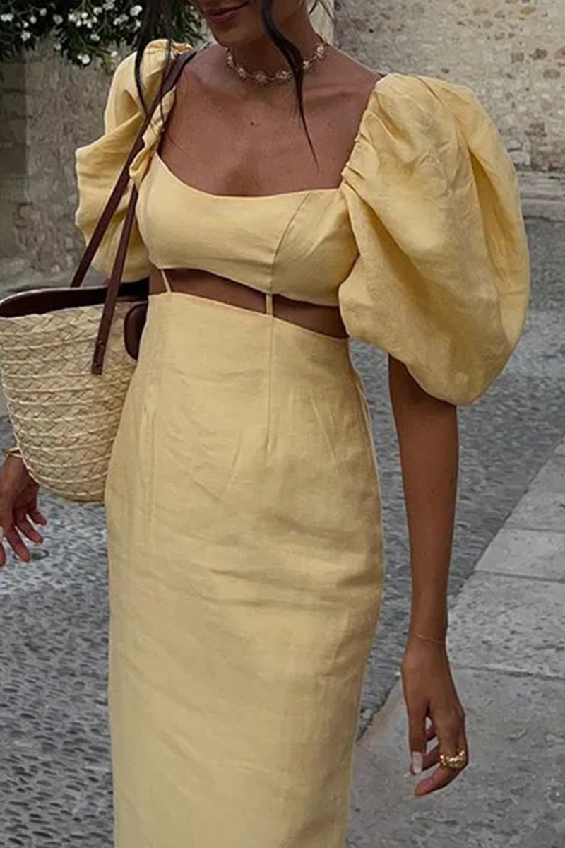 Close-up of a woman in a yellow linen dress with puff sleeves and a cut-out detail.
