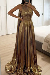 Woman wearing a long, flowing gold one-shoulder dress with intricate pleating.