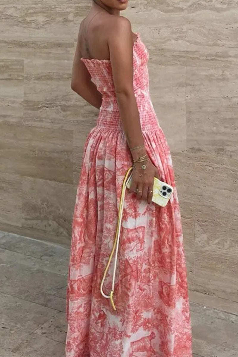 Back view of a woman in a pink and white patterned strapless maxi dress, holding a phone with a yellow strap.