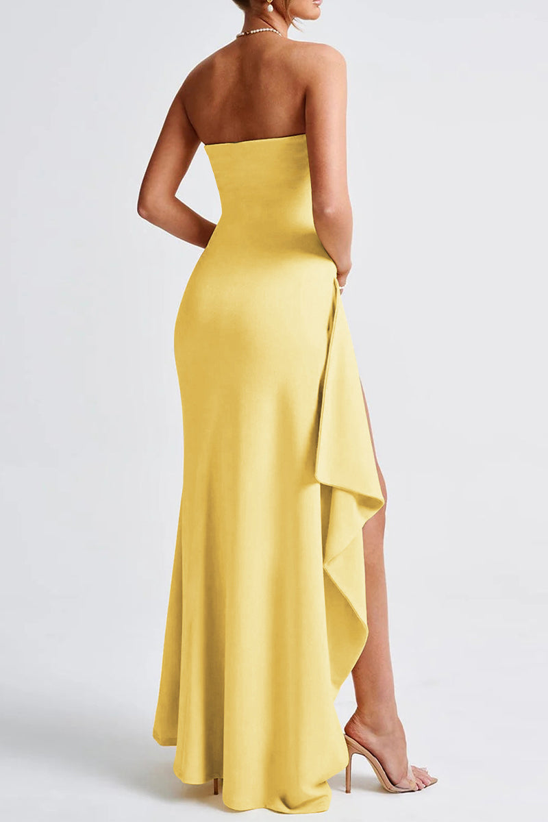 A woman's back is shown wearing a yellow strapless gown with a high slit and draped detail.
