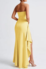 A woman's back is shown wearing a yellow strapless gown with a high slit and draped detail.