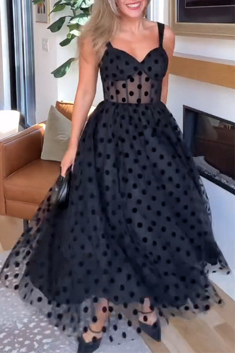 Woman in a black polka dot tulle midi dress with a sweetheart neckline and spaghetti straps, twirling.