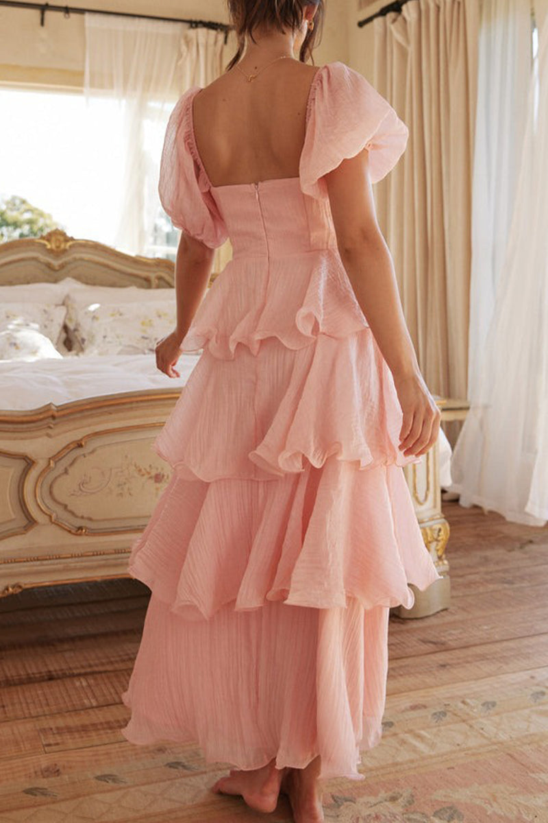 Back view of a woman in a pink tiered ruffle dress with puff sleeves.