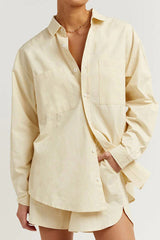Close-up of a person wearing a cream oversized shirt with chest pockets.