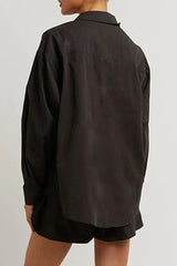 Back view of a person wearing a black oversized button-up shirt.
