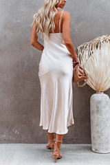 Back view of a woman in a white satin slip dress with spaghetti straps and a side slit.