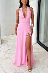 A woman wearing a pink halter maxi dress with a high slit and a cinched waist.