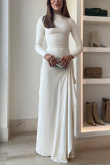 A woman poses with a silver clutch in front of her ivory dress.