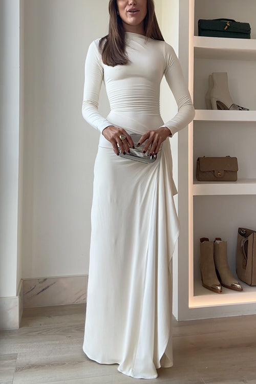 A woman poses with a silver clutch in front of her ivory dress.
