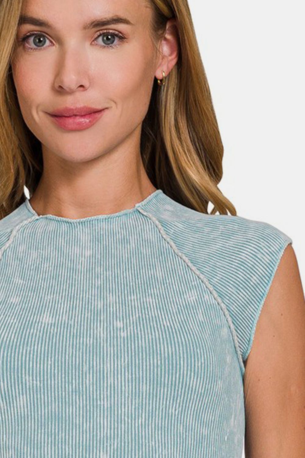 Close-up of the neckline and shoulder of a woman wearing a teal and white acid wash ribbed knit cropped mock neck top.