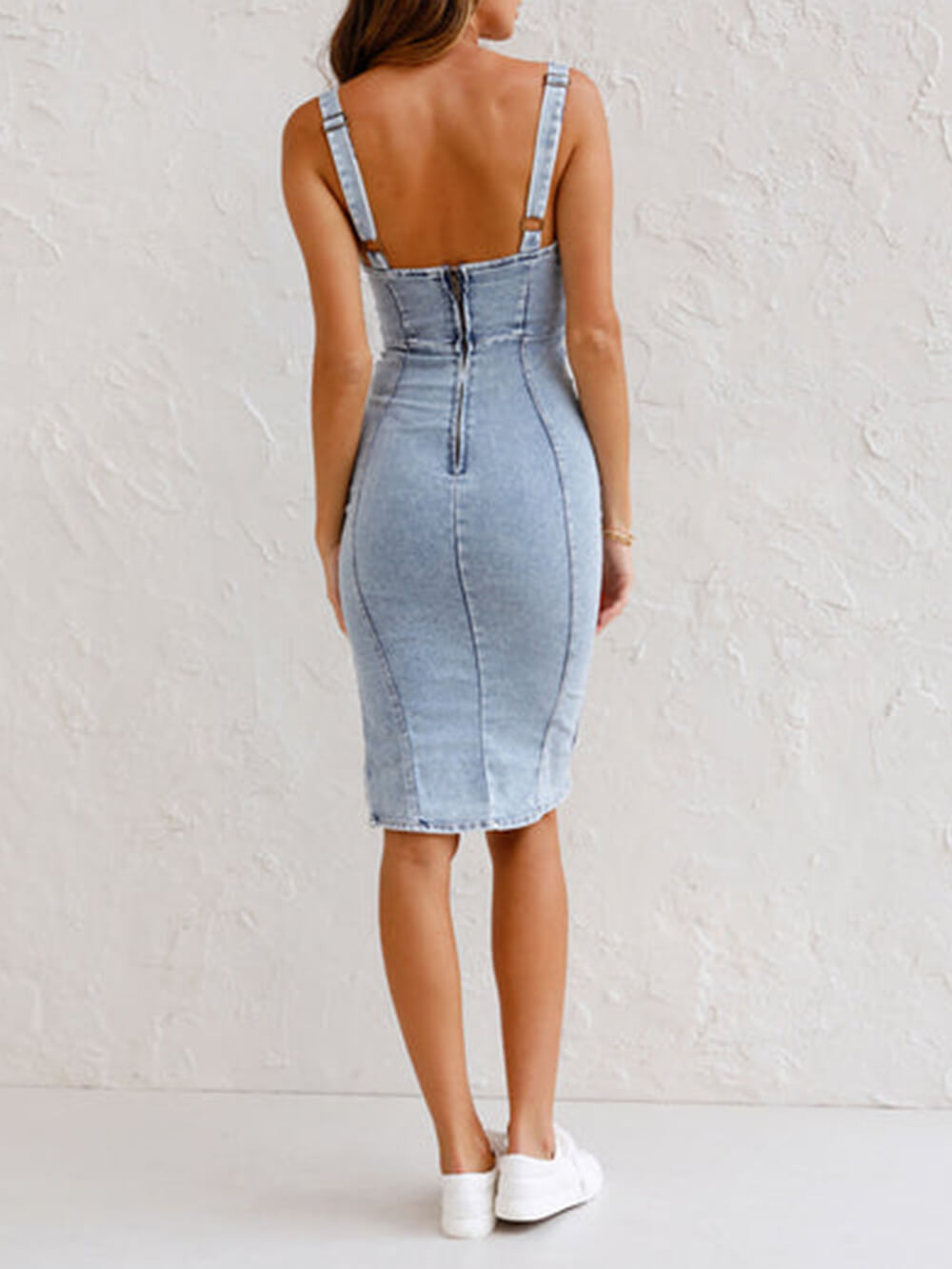 Back view of a woman wearing a light blue denim sleeveless sheath dress with a zipper closure.