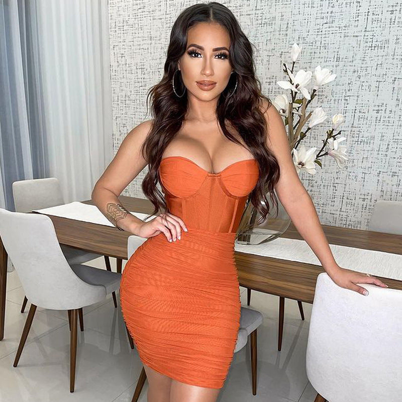 woman wearing an orange ruched mini dress with a corset bodice