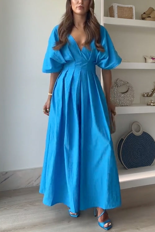 Full body shot of a woman in a blue maxi dress with puff sleeves.