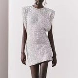 A model wearing a short, silver sequined dress with cap sleeves and shoulder pads.