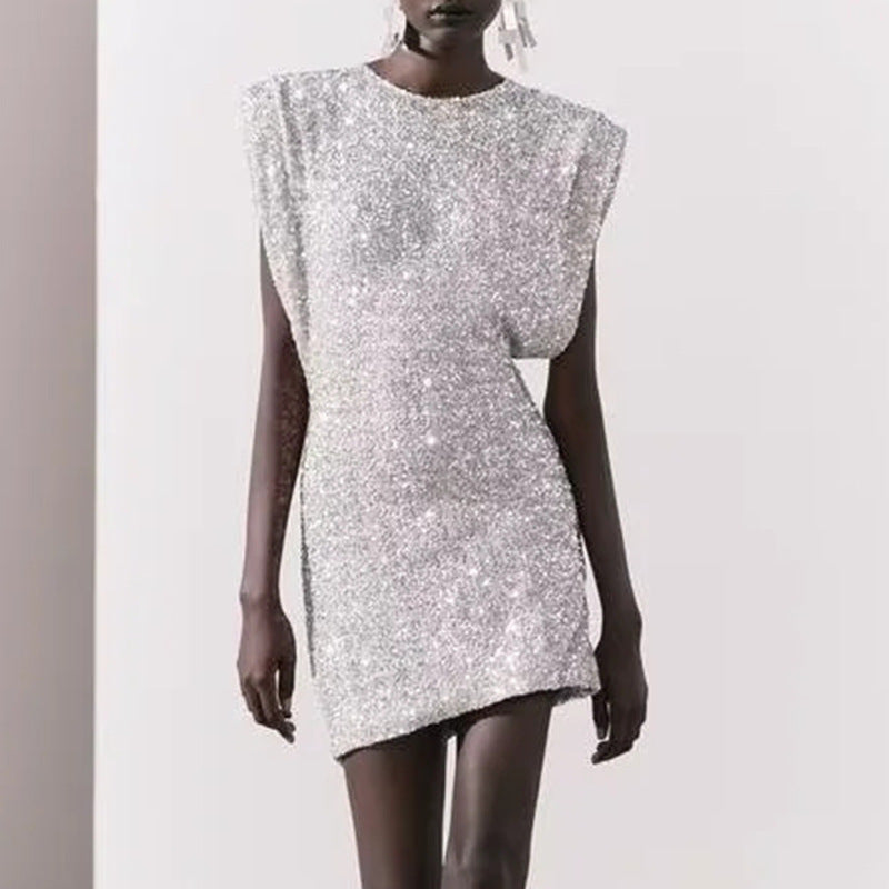 A model wearing a short, silver sequined dress with cap sleeves and shoulder pads.