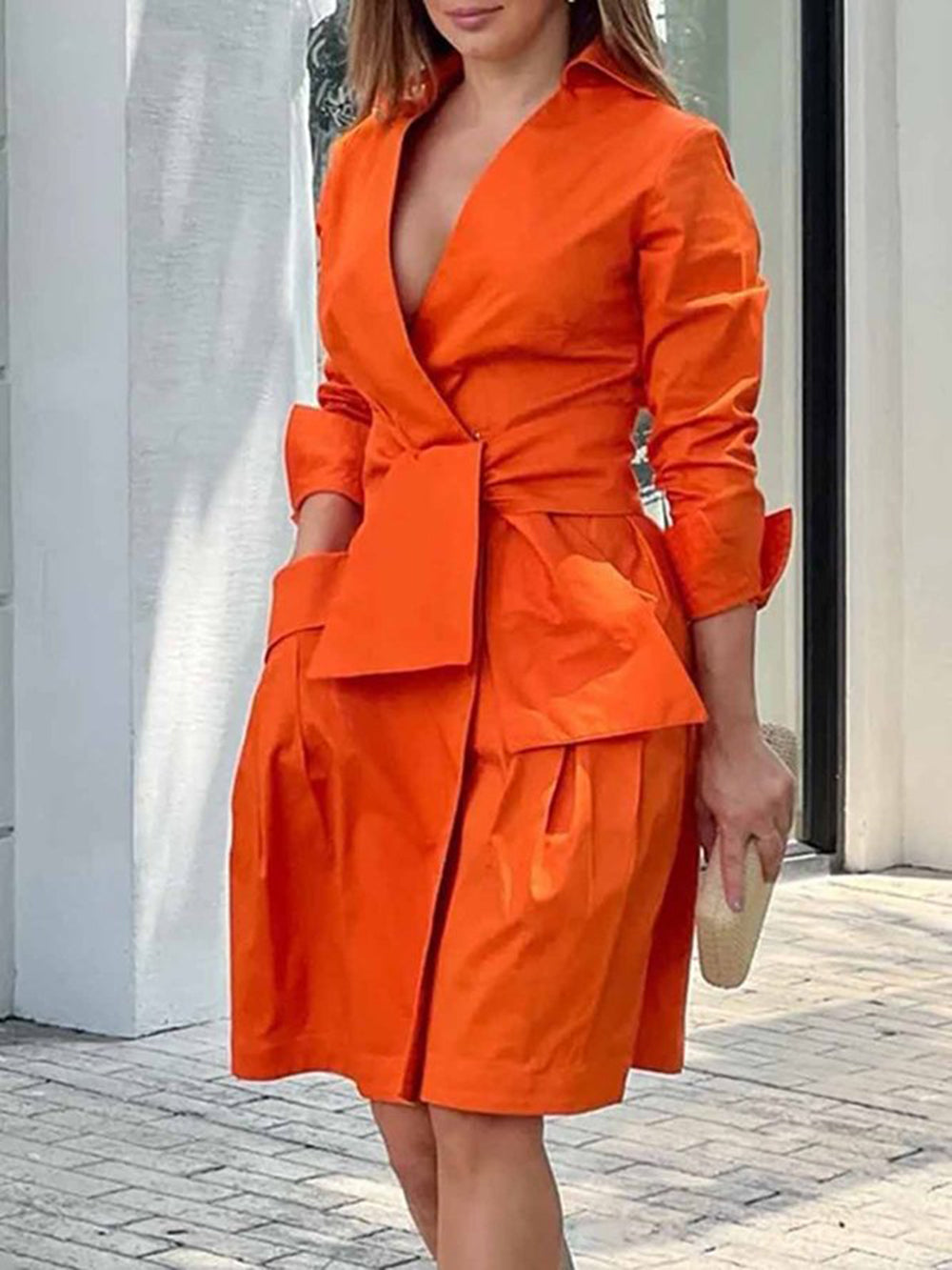 woman wearing an orange wrap dress with a tie waist and pleated skirt