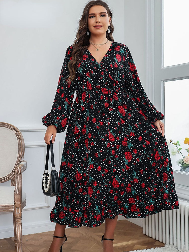 A plus-size woman holding a black beaded handbag, wearing a black floral and polka dot midi dress.