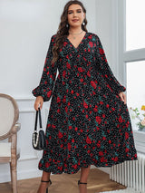 A plus-size woman holding a black beaded handbag, wearing a black floral and polka dot midi dress.