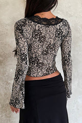 Back view of a woman wearing a black and beige lace long-sleeved top with a plunging neckline and a black skirt