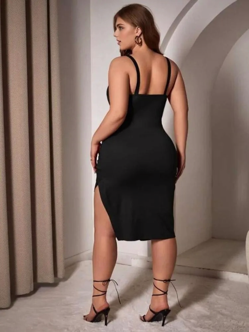 Back view of a plus-size woman in a black V-neck, spaghetti strap dress with a corset detail and an asymmetrical hem with a thigh slit.