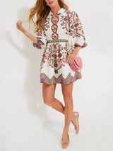 A woman wearing the paisley print dress, paired with a pink crossbody bag and ballet flats.
