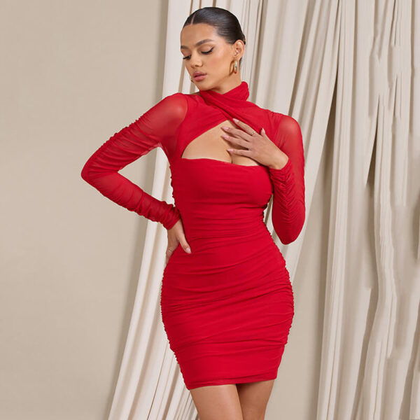 Woman touching her chest while wearing a red ruched mini dress with a high neck and cut-out detail