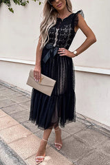woman in a black lace and tulle midi dress with a bow, sunglasses