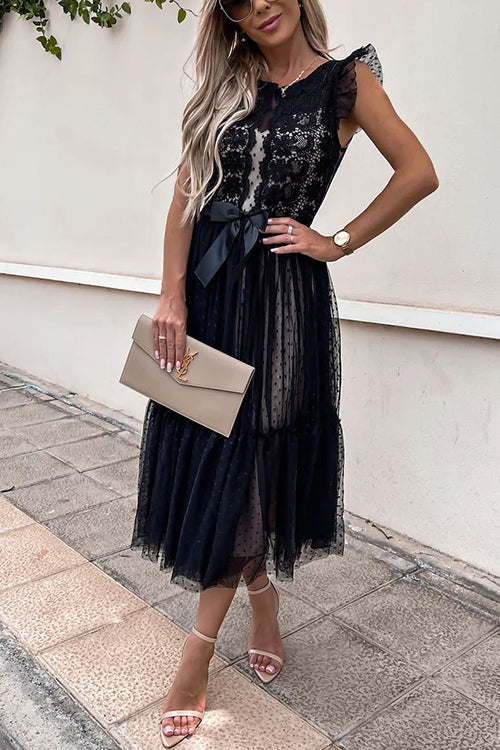woman in a black lace and tulle midi dress with a bow, sunglasses
