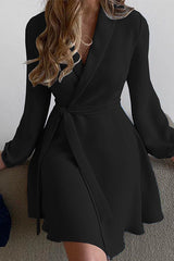 woman wearing a black wrap dress with a belted waist and long sleeves