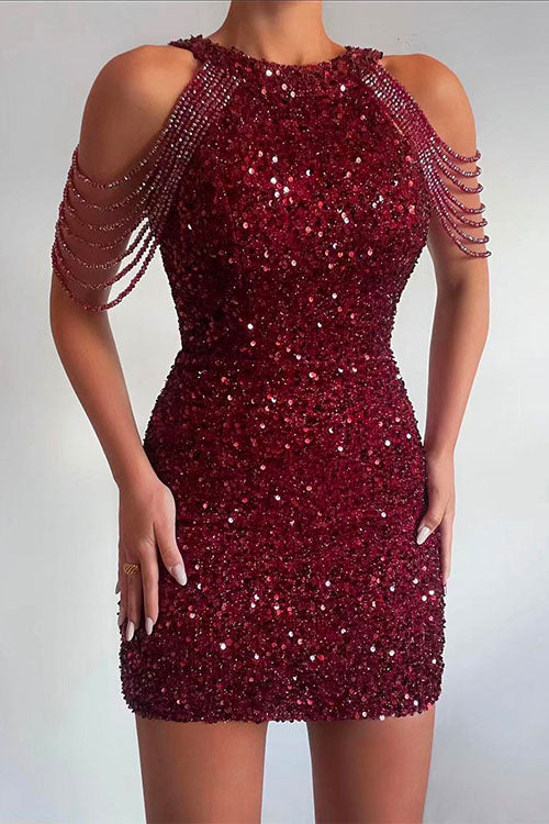 A woman in a burgundy sequined mini dress with beaded shoulder straps.