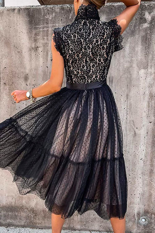 Back view of a woman in a black polka dot midi dress with a lace top.