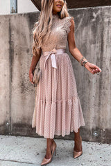 Close-up of a woman in a pink polka dot midi dress with lace detailing.
