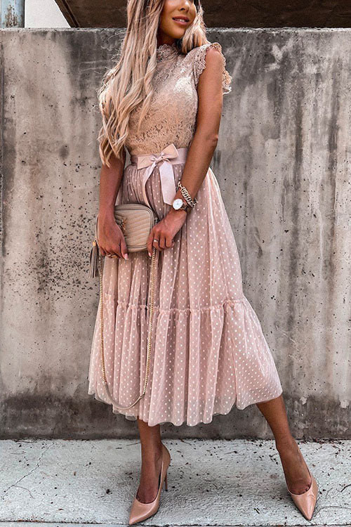Woman posing in a pink polka dot midi dress with a lace top.