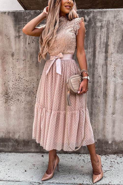 Woman adjusting her hair while wearing a pink polka dot midi dress.