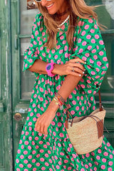 Close-up of a woman in a green floral print dress, showing accessories like a pink watch and bracelets.