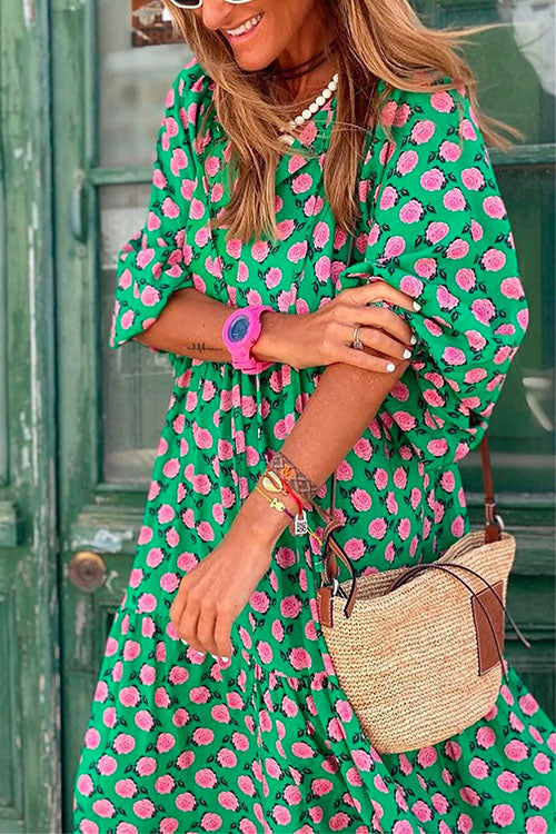 Close-up of a woman in a green floral print dress, showing accessories like a pink watch and bracelets.