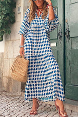 Woman in a blue and white diamond print dress with puff sleeves and a tiered skirt, holding a straw bag.