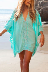 Woman wearing a turquoise beach cover-up on a sandy beach