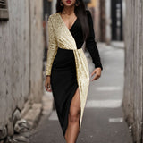 Woman wearing a black and gold sequined wrap dress with a high slit, standing in an alley.