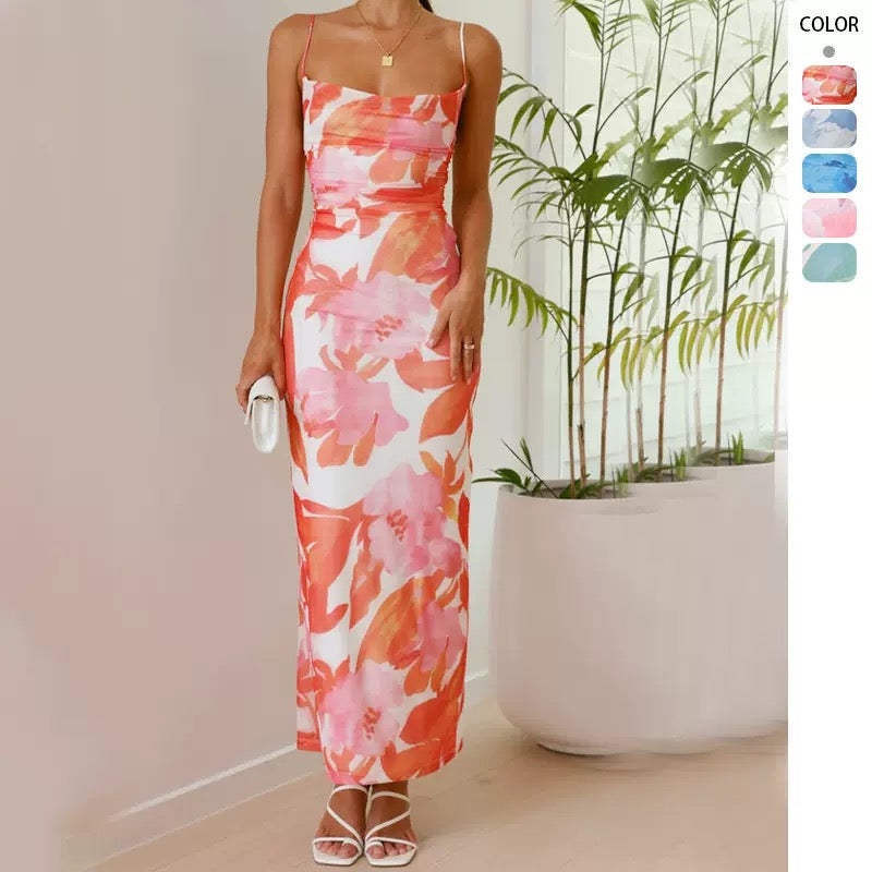 Woman wearing a long floral print dress with spaghetti straps and a ruched bodice.