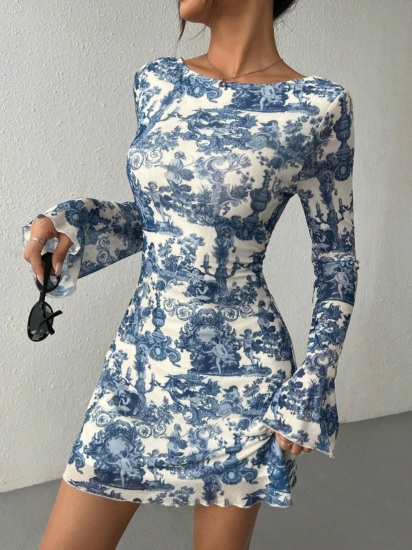 woman wearing a blue and white toile print sheer mini dress with bell sleeves
