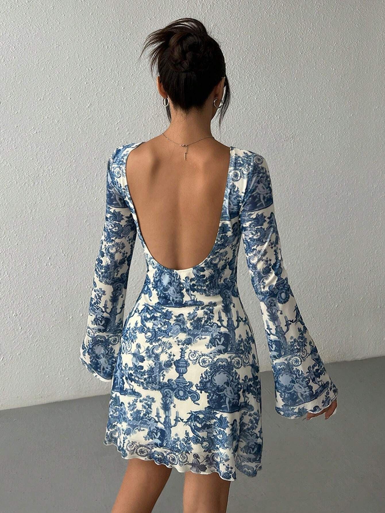 back view of a woman in a blue and white toile print sheer mini dress with an open back