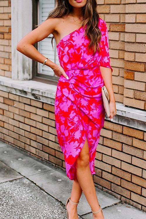 full body shot of a woman in a pink and red floral one-shoulder sheath dress, paired with beige heels and a clutch