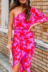 woman wearing a pink and red floral one-shoulder sheath dress with a ruched waist and tulip hem, holding a beige clutch