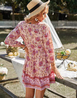 Back view of a woman in a pink floral print dress and straw hat.