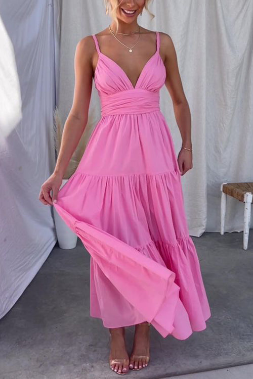 A woman modeling a pink tiered maxi dress with spaghetti straps and a ruched bodice.