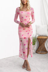 Front view of a woman posing in a pink floral mesh dress with a square neckline and long sleeves