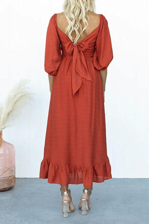 back view of a woman wearing a red midi dress with a bow detail on the back