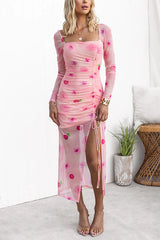 Woman wearing a pink floral mesh dress with long sleeves and a thigh-high slit