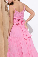The back of a pink tiered maxi dress showing a tie detail at the waist.